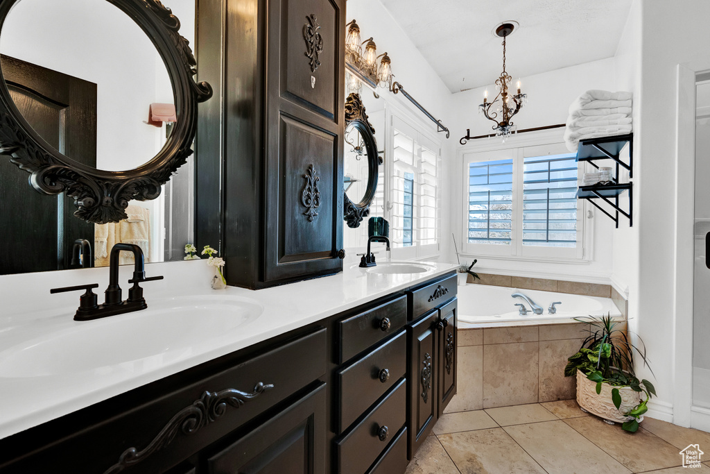 Bathroom featuring double sink vanity, tile flooring, a relaxing tiled bath, and a chandelier