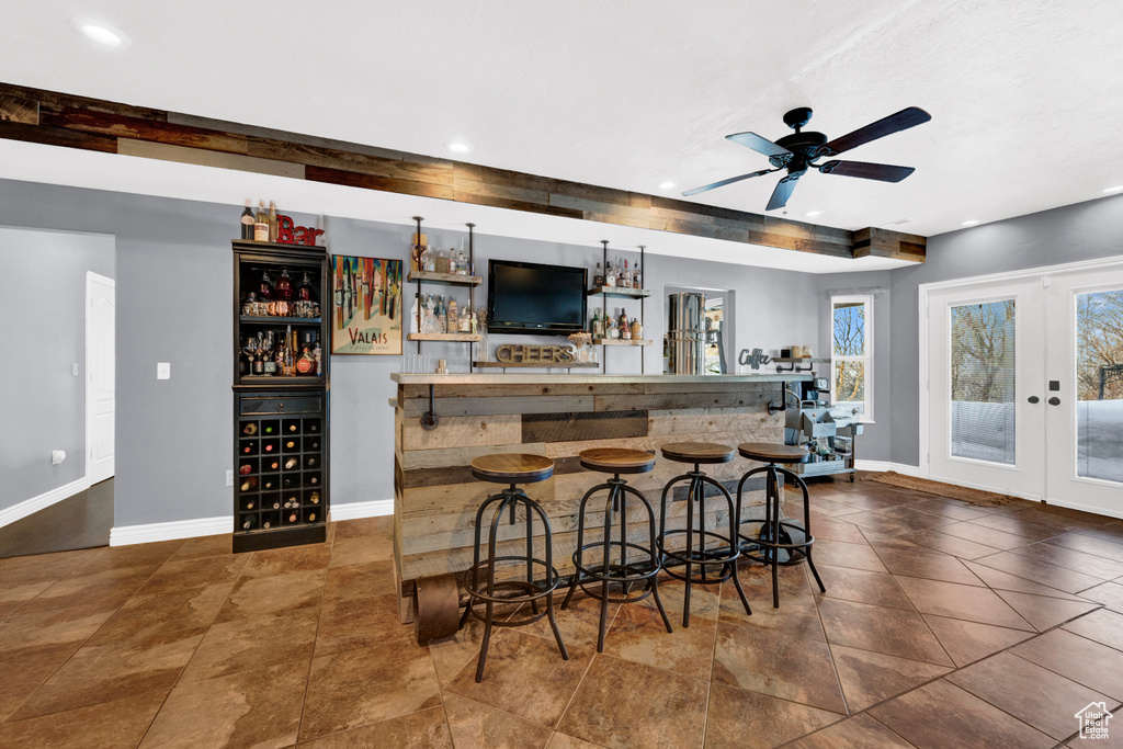 Bar with dark tile floors, ceiling fan, and french doors