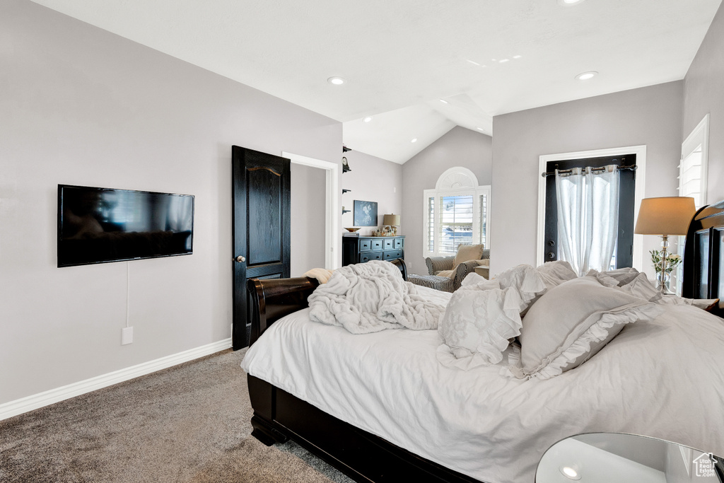 Bedroom with dark colored carpet and lofted ceiling