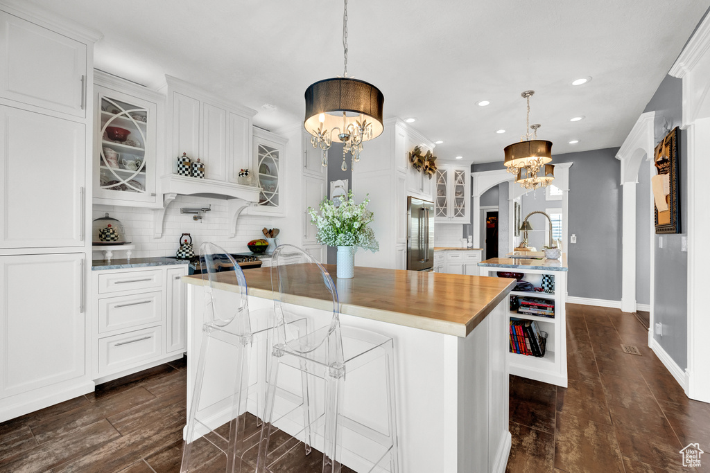 Kitchen with white cabinets, pendant lighting, a center island, and backsplash
