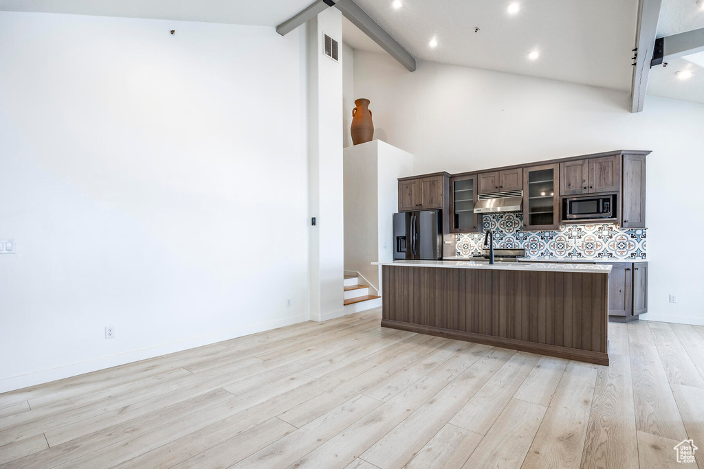 Kitchen with appliances with stainless steel finishes, high vaulted ceiling, light wood-type flooring, and beamed ceiling