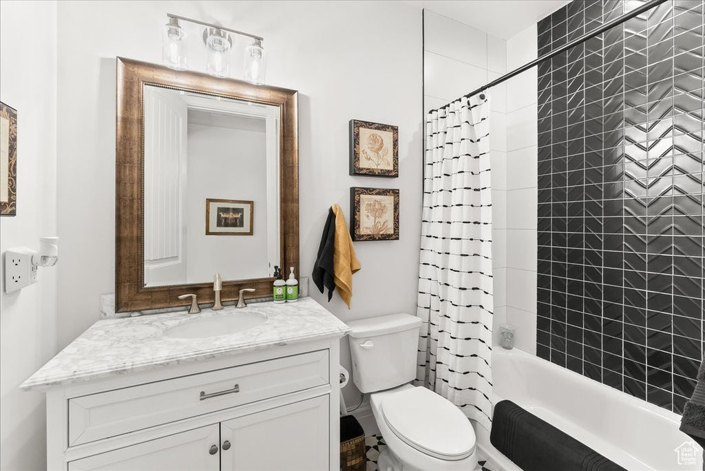 Full bathroom with shower / bath combo with shower curtain, toilet, and vanity with extensive cabinet space