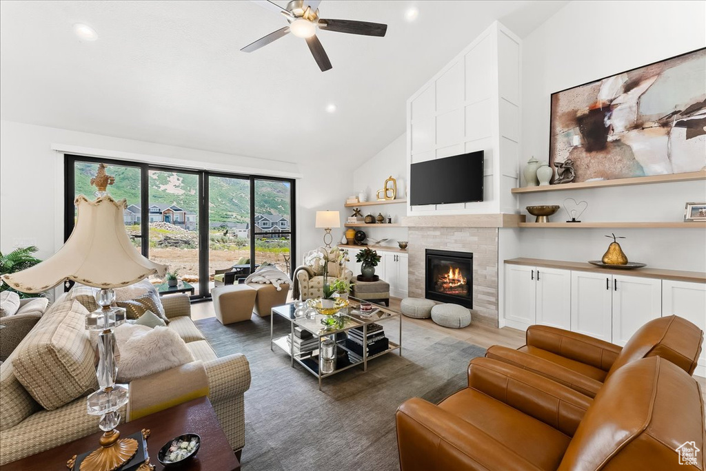 Living room featuring a fireplace, dark hardwood / wood-style floors, ceiling fan, and high vaulted ceiling