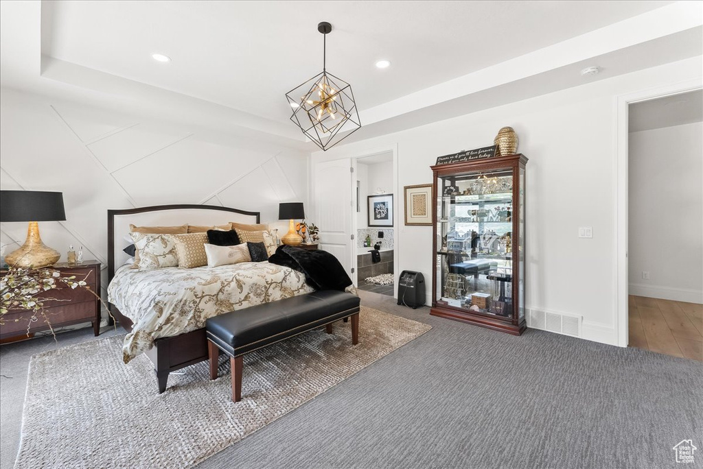 Bedroom with an inviting chandelier, hardwood / wood-style floors, and a tray ceiling