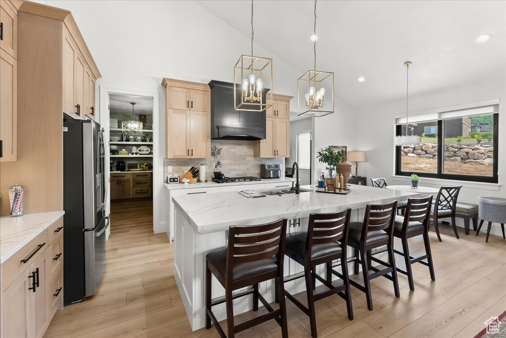 Kitchen featuring plenty of natural light, light hardwood / wood-style flooring, tasteful backsplash, and stainless steel fridge