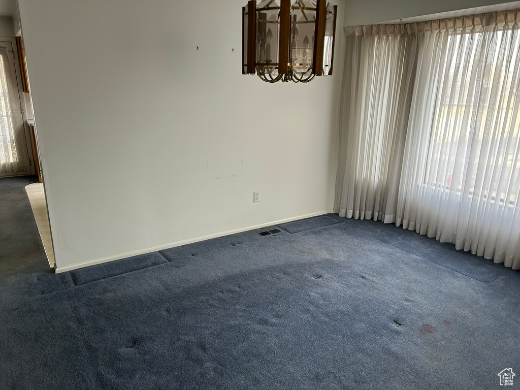 Carpeted empty room featuring a chandelier