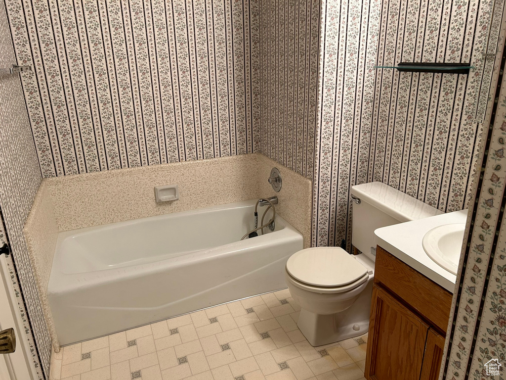 Bathroom featuring a tub, vanity, tile flooring, and toilet