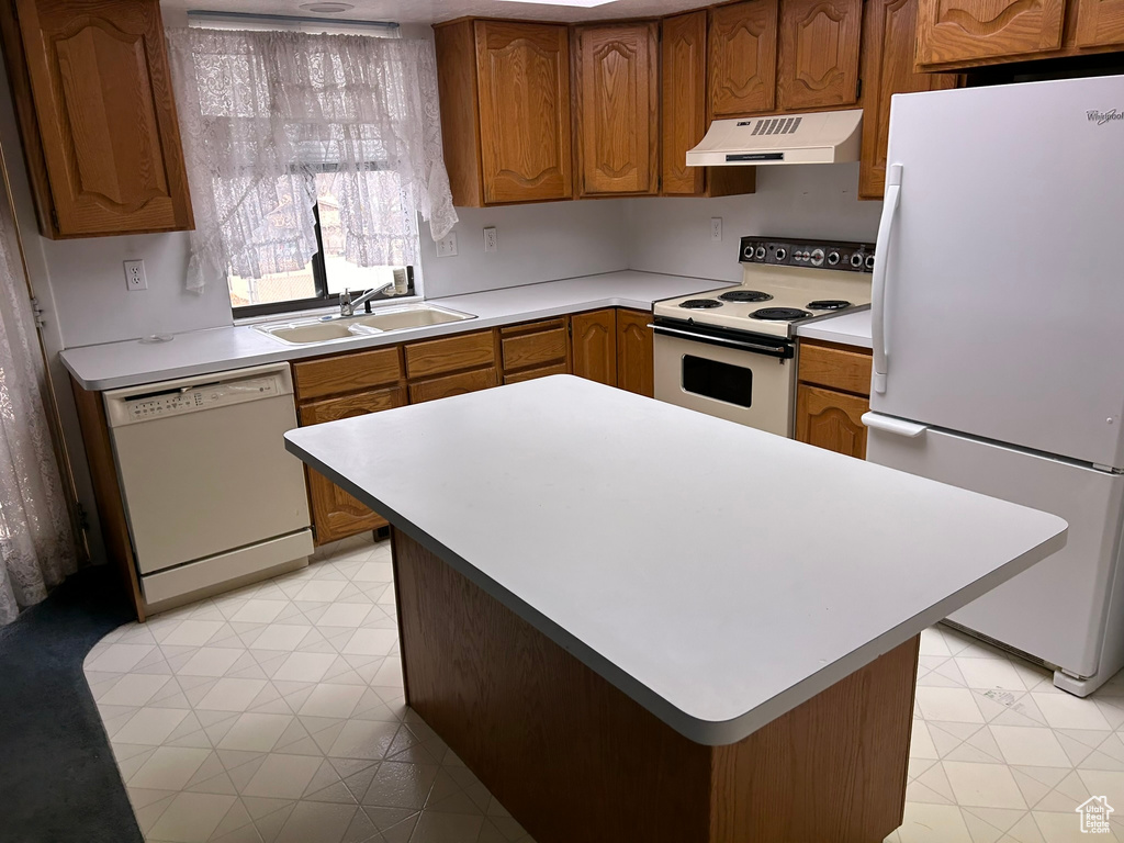 Kitchen featuring white appliances, sink, light tile floors, and a center island