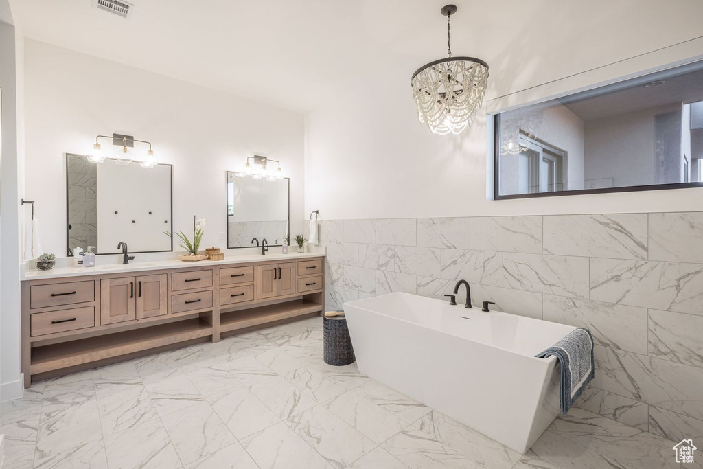 Bathroom with tile walls, a notable chandelier, tile floors, and a bath to relax in
