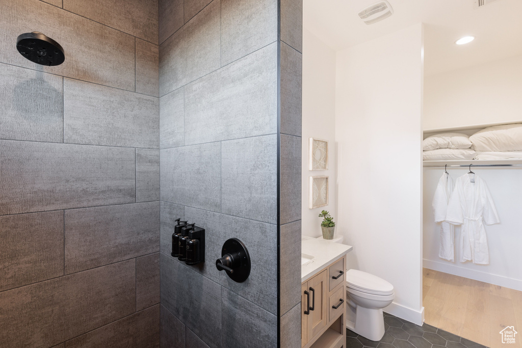 Bathroom featuring vanity, toilet, hardwood / wood-style floors, and tiled shower