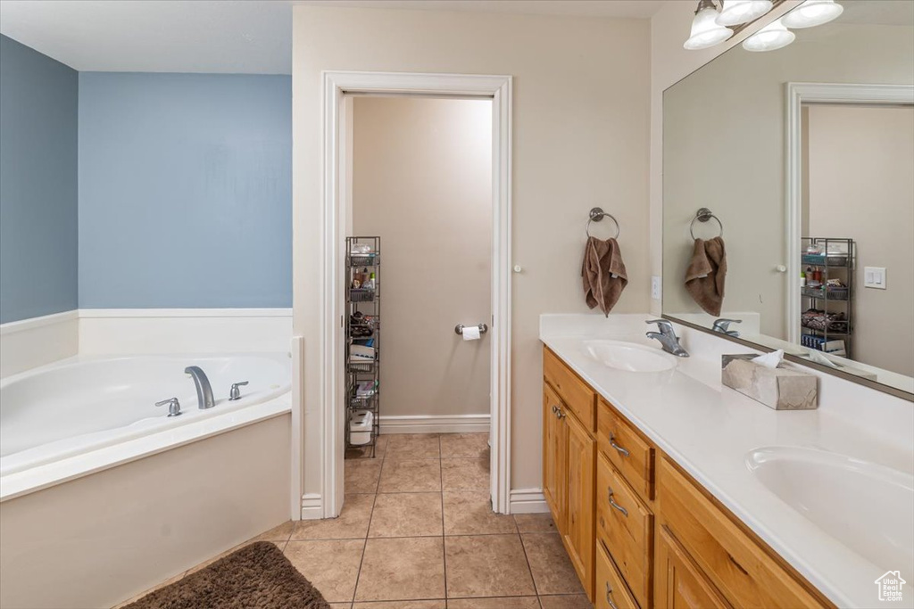 Bathroom featuring a bathing tub, dual bowl vanity, and tile floors