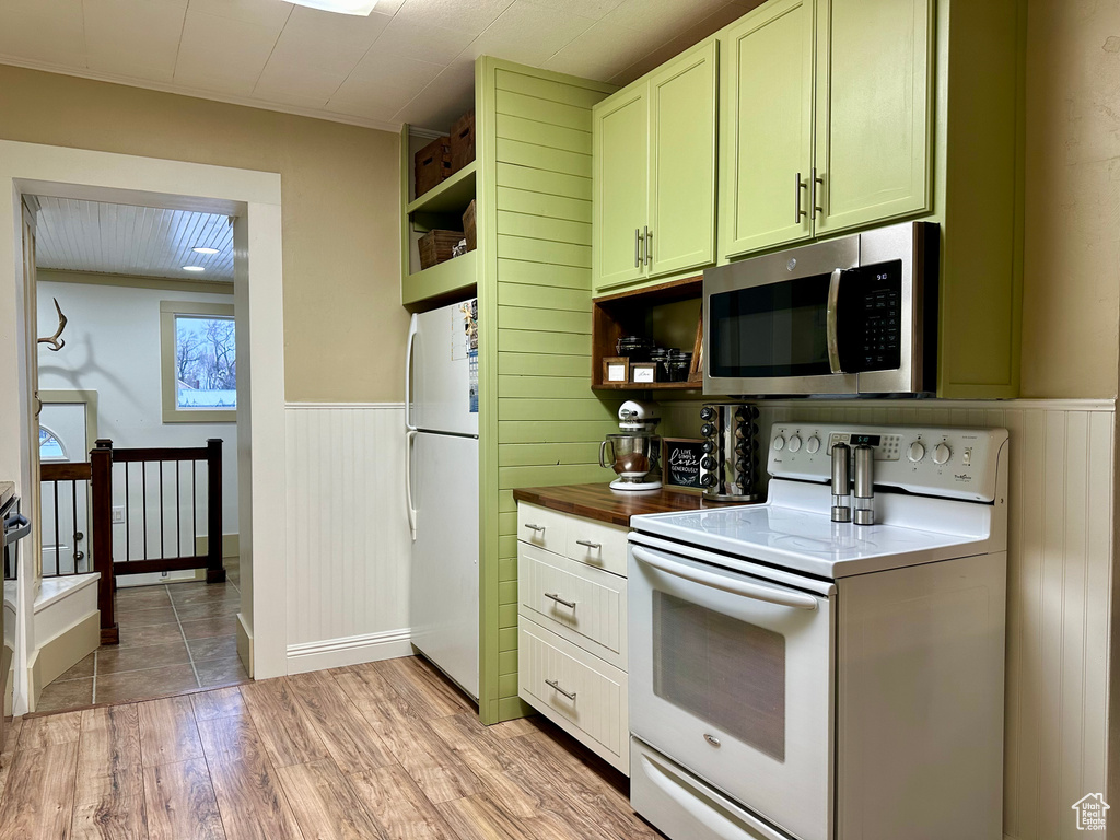 Kitchen featuring white appliances, light hardwood / wood-style floors, backsplash, and white cabinetry