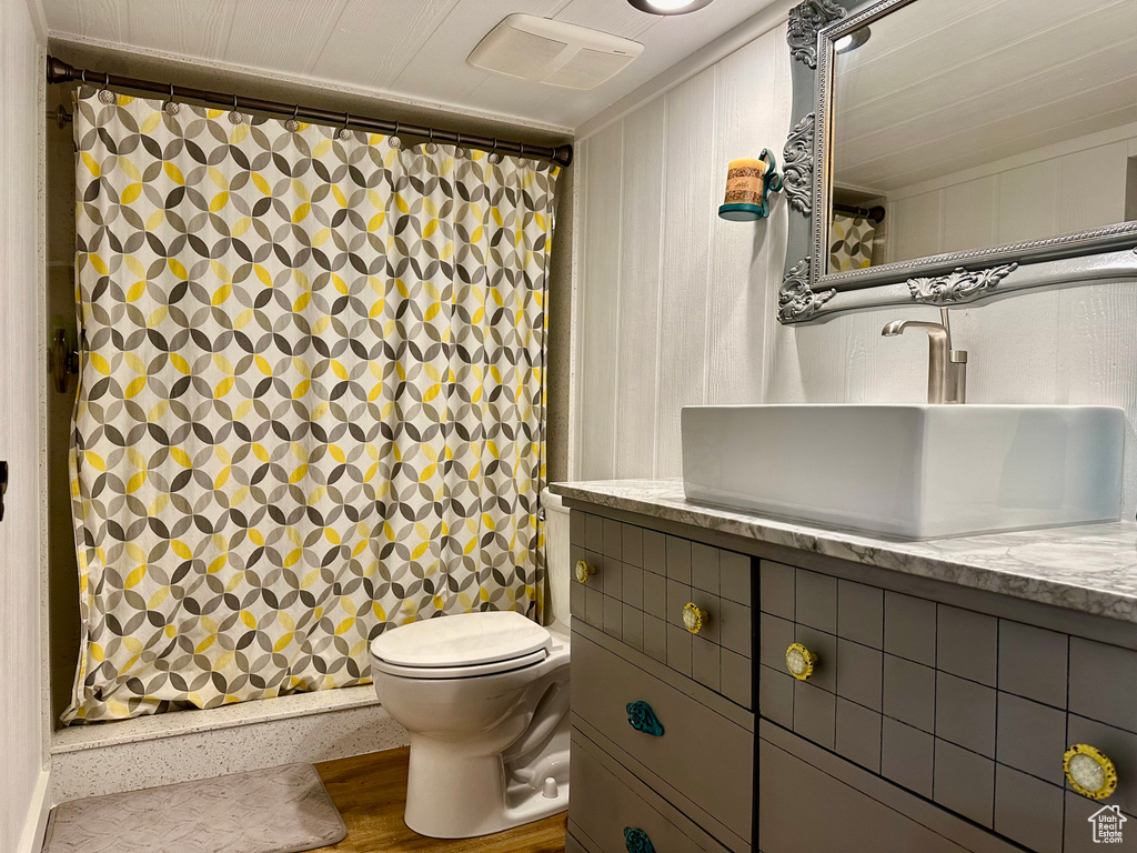 Bathroom featuring wood-type flooring, oversized vanity, and toilet