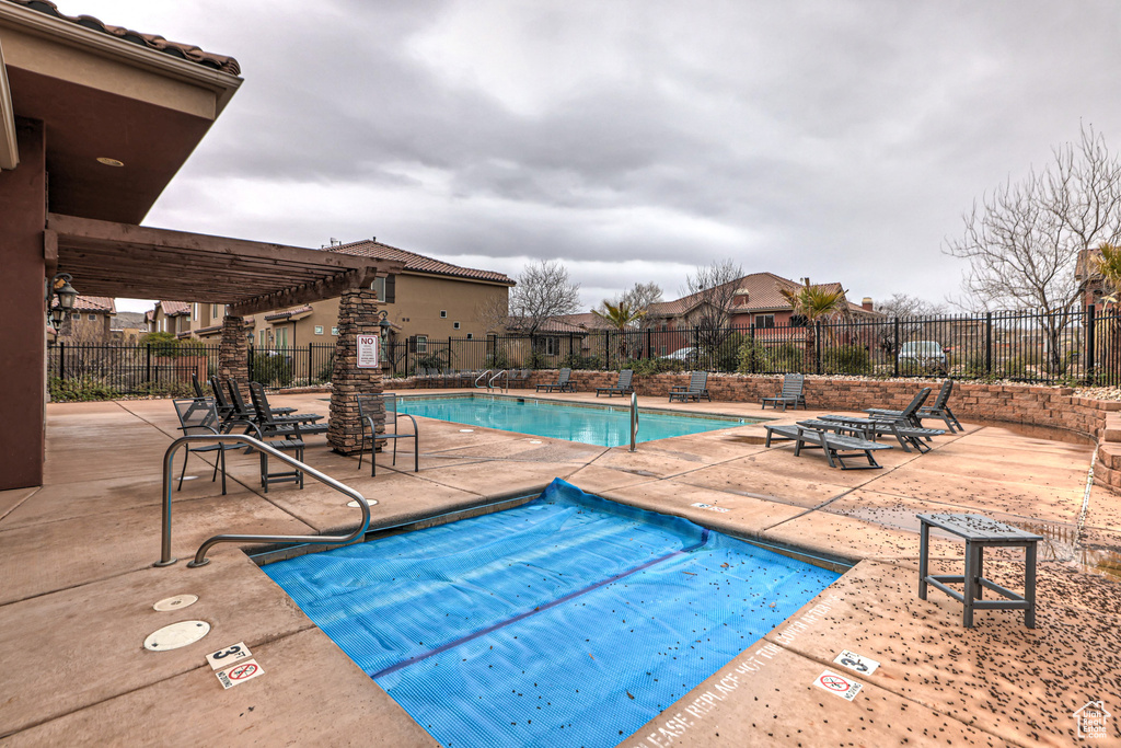 View of pool with a pergola and a patio