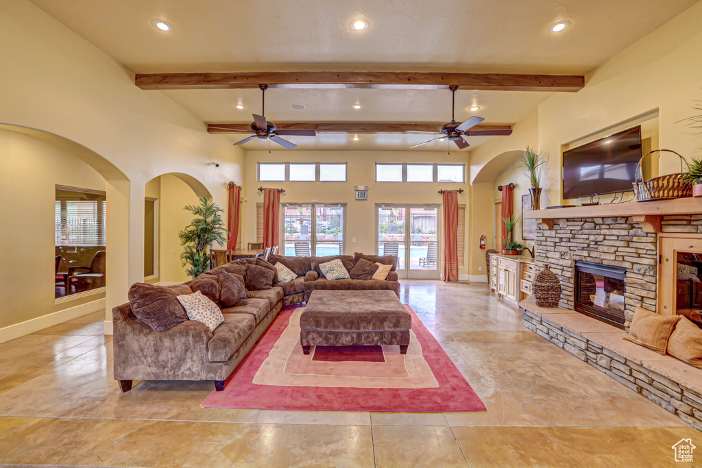Tiled living room with beam ceiling, a fireplace, ceiling fan, and a towering ceiling