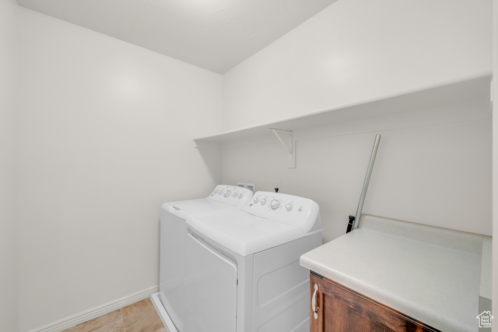 Washroom with cabinets, independent washer and dryer, and light tile floors