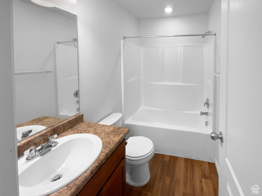 Full bathroom featuring hardwood / wood-style flooring, shower / bathtub combination, vanity, and toilet