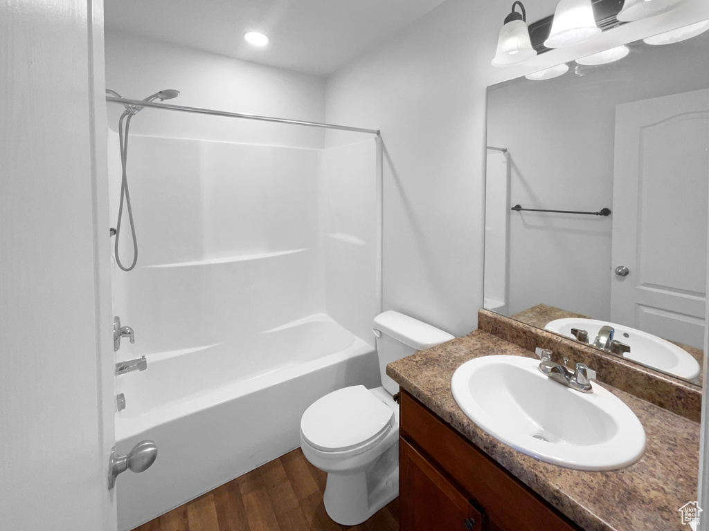 Full bathroom with vanity, toilet, shower / bath combination, and wood-type flooring