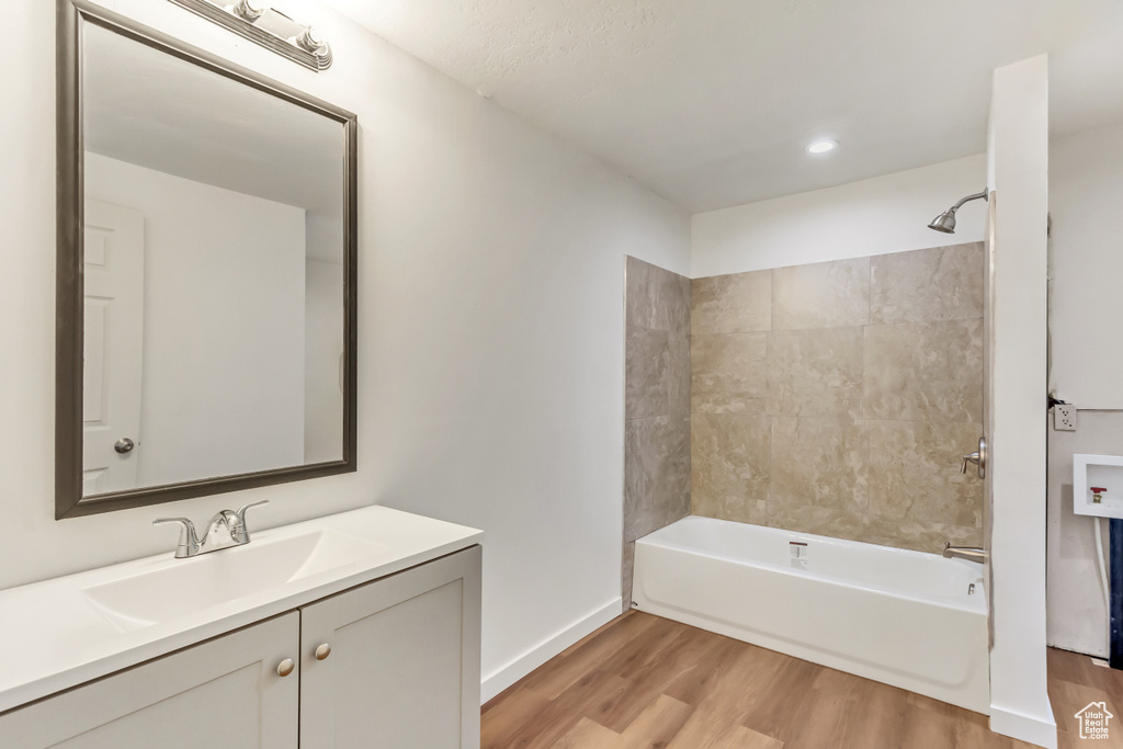 Bathroom with vanity, hardwood / wood-style floors, and tiled shower / bath
