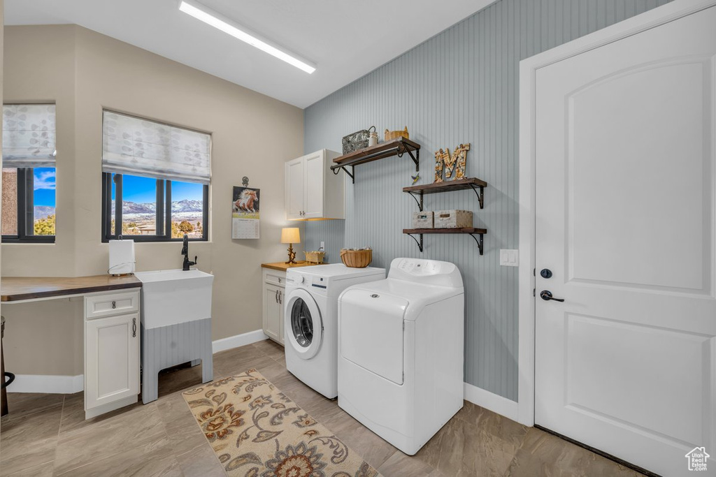 Laundry area featuring light tile flooring, washer and clothes dryer, and cabinets