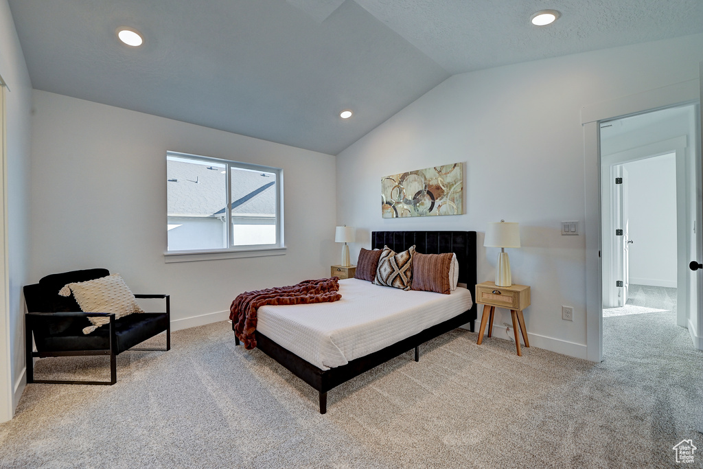 Bedroom with light colored carpet and lofted ceiling