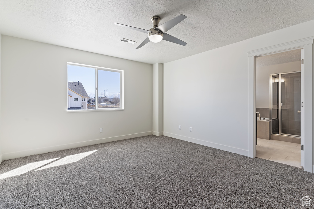 Carpeted spare room with ceiling fan and a textured ceiling