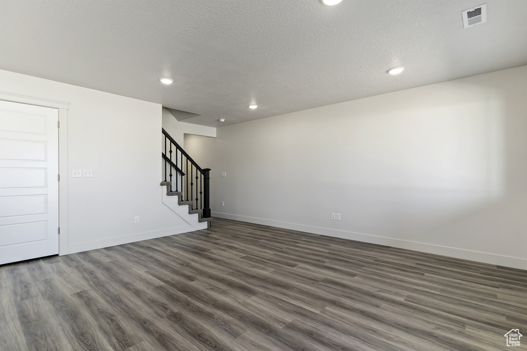 Empty room featuring dark hardwood / wood-style flooring and a textured ceiling