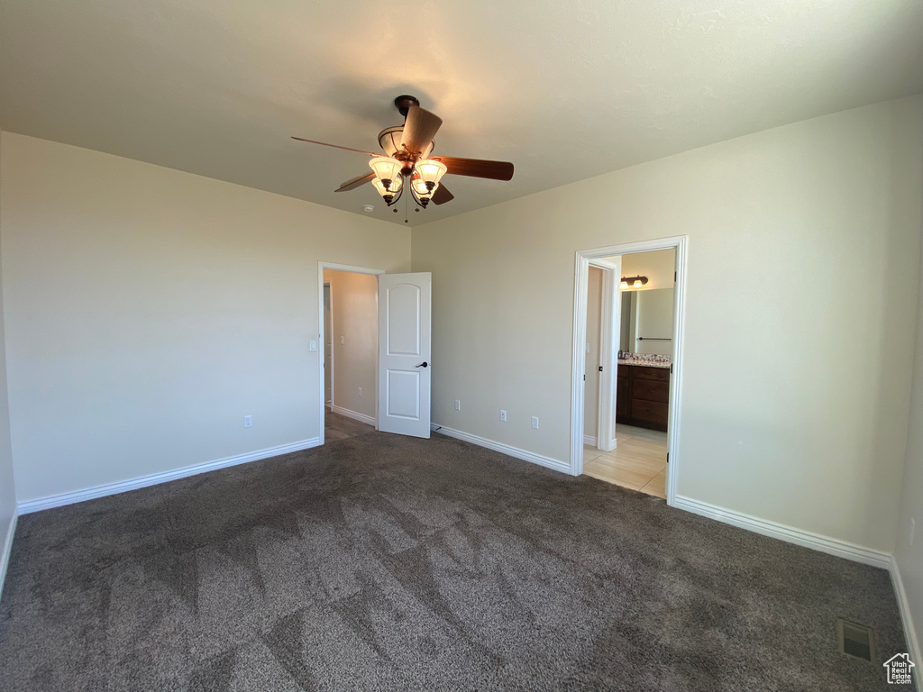 Unfurnished bedroom featuring connected bathroom, ceiling fan, and carpet flooring