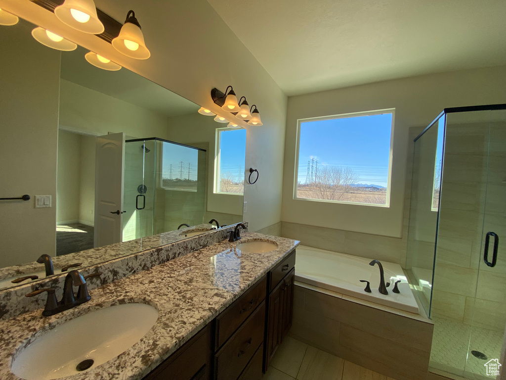 Bathroom featuring dual bowl vanity, tile floors, and separate shower and tub
