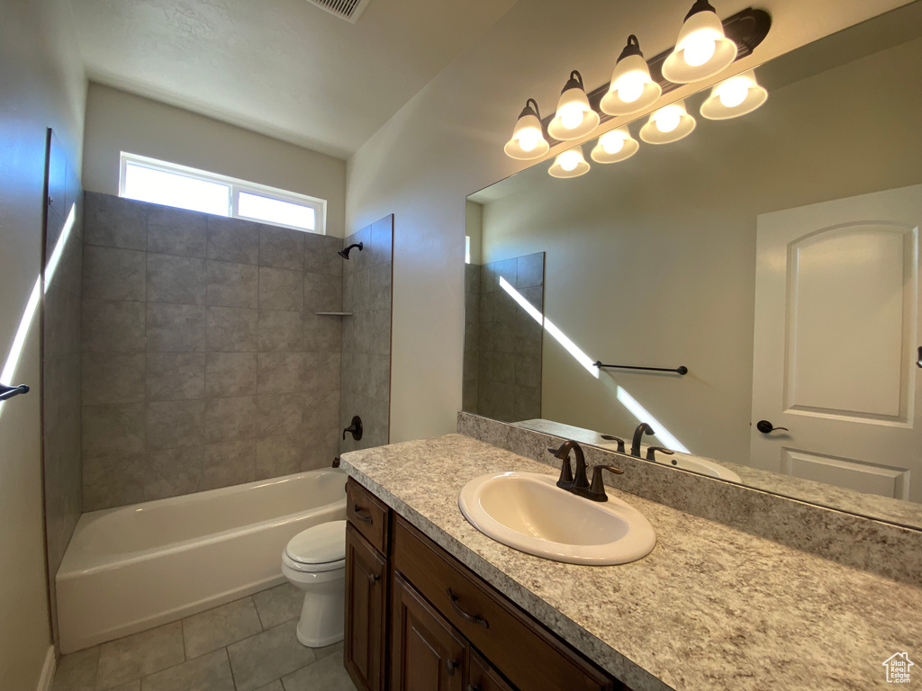 Full bathroom with tiled shower / bath, vanity, tile flooring, and toilet