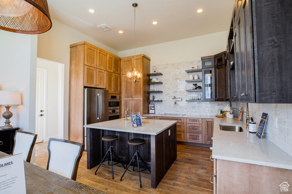 Kitchen featuring tasteful backsplash, hardwood / wood-style floors, hanging light fixtures, and a kitchen island