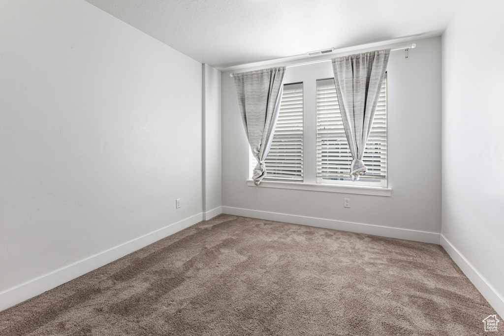 Unfurnished room with a healthy amount of sunlight and light colored carpet