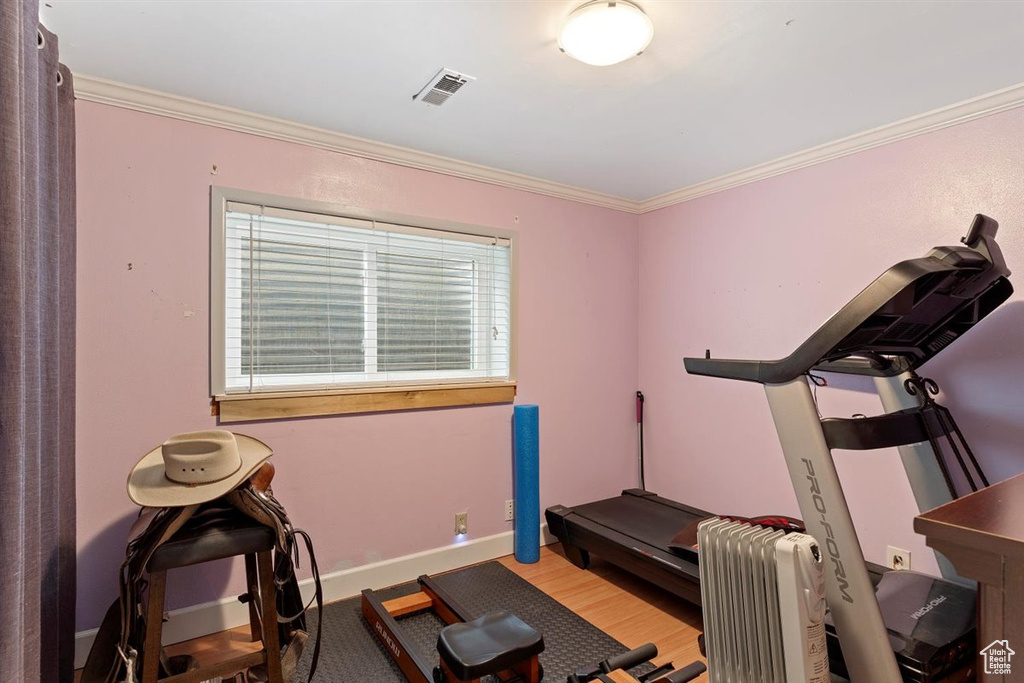Workout room with light hardwood / wood-style floors, ornamental molding, and radiator heating unit