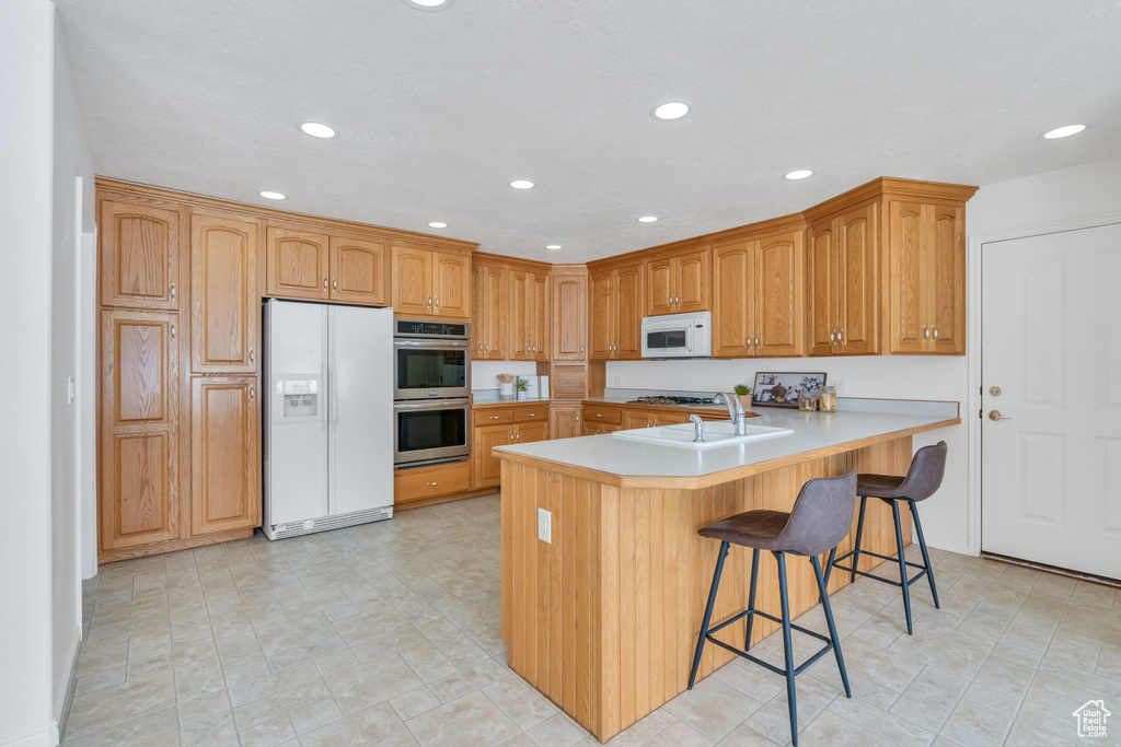 Kitchen with appliances with stainless steel finishes, kitchen peninsula, light tile floors, and a kitchen bar