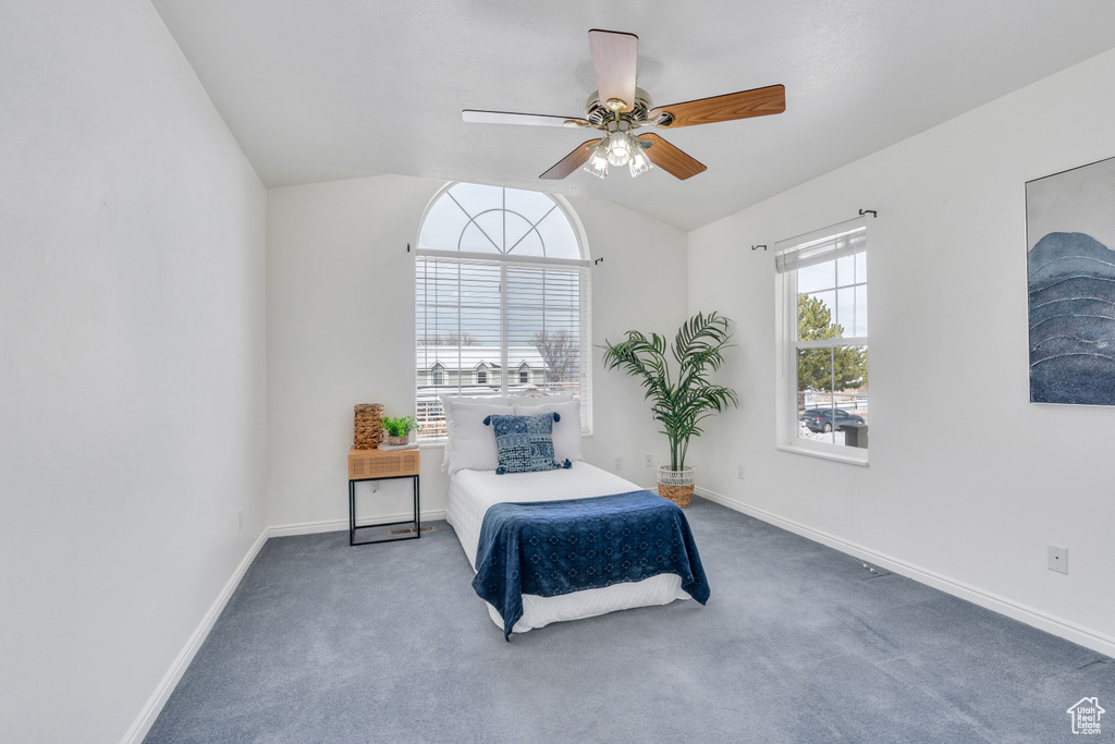 Bedroom with dark colored carpet, vaulted ceiling, and ceiling fan