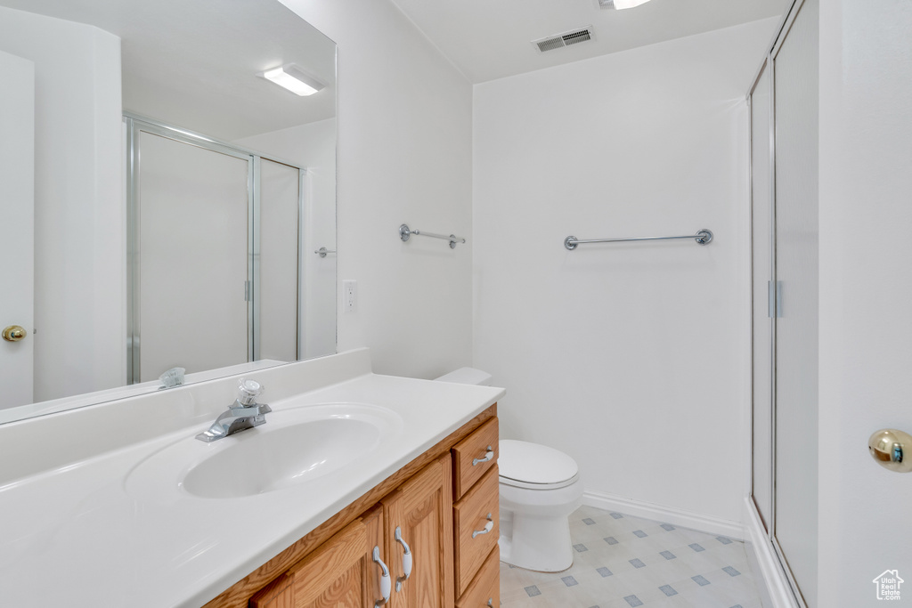 Bathroom featuring tile flooring, a shower with shower door, large vanity, and toilet