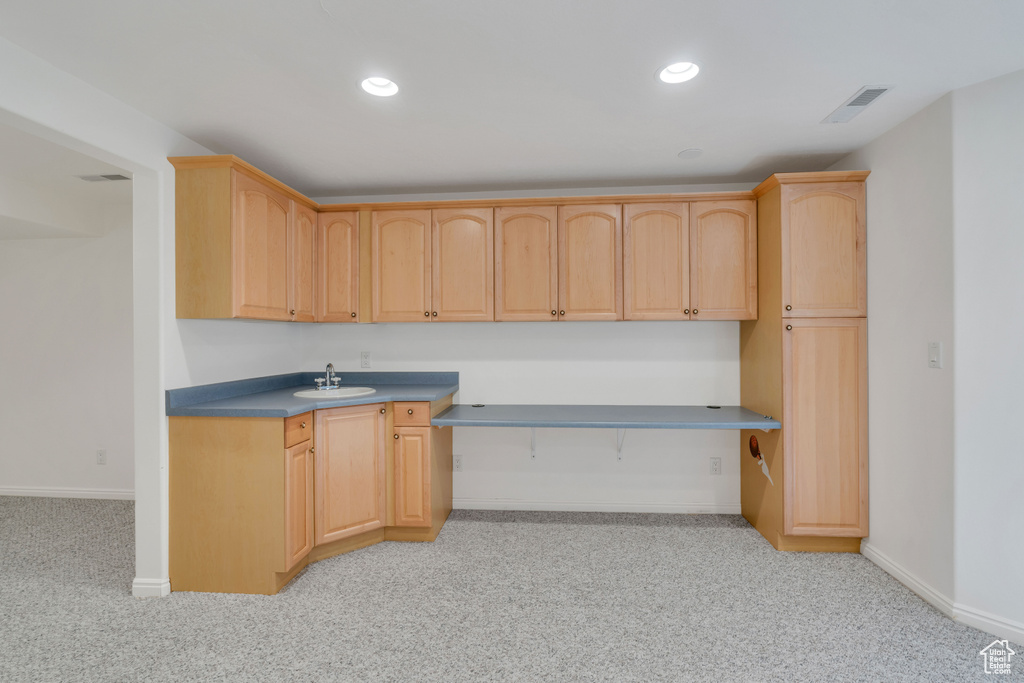 Kitchen featuring light colored carpet, sink, and light brown cabinets