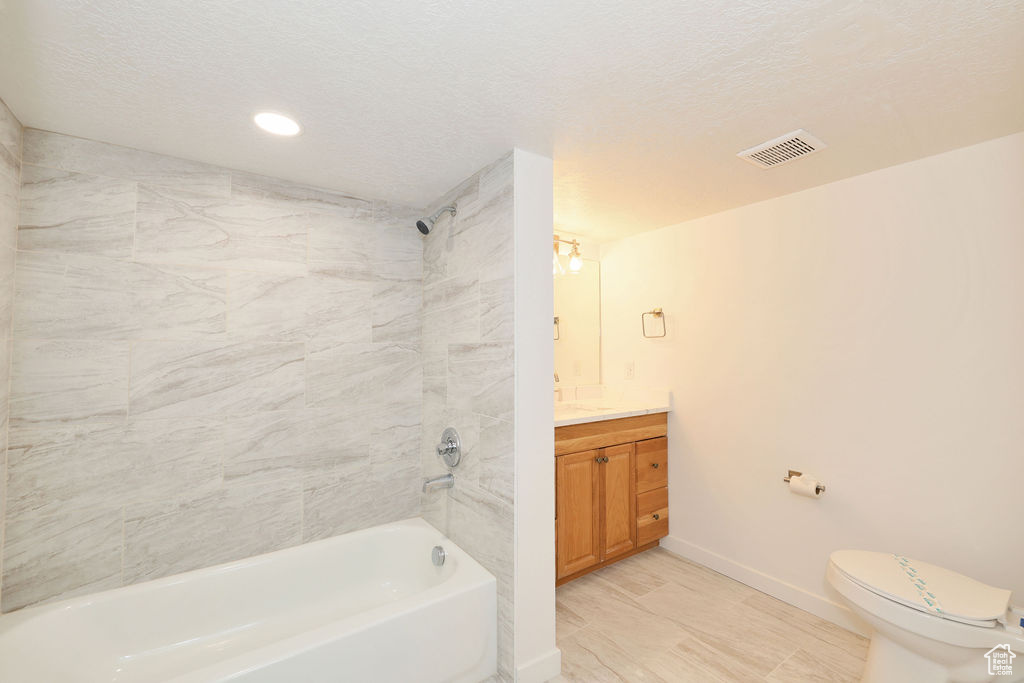Full bathroom featuring vanity, toilet, tiled shower / bath combo, and tile floors