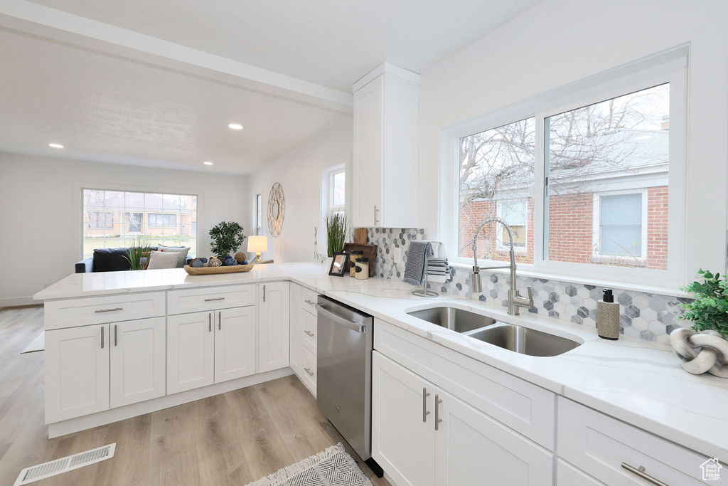 Kitchen featuring kitchen peninsula, light wood-type flooring, backsplash, and stainless steel dishwasher