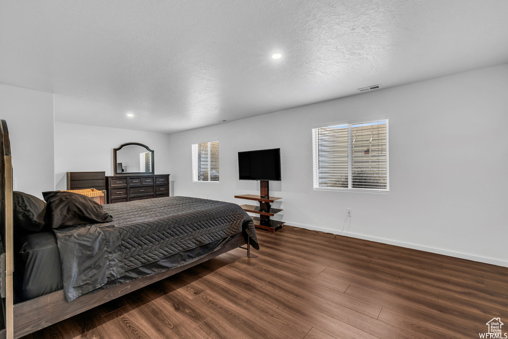 Bedroom with dark hardwood / wood-style flooring and a textured ceiling