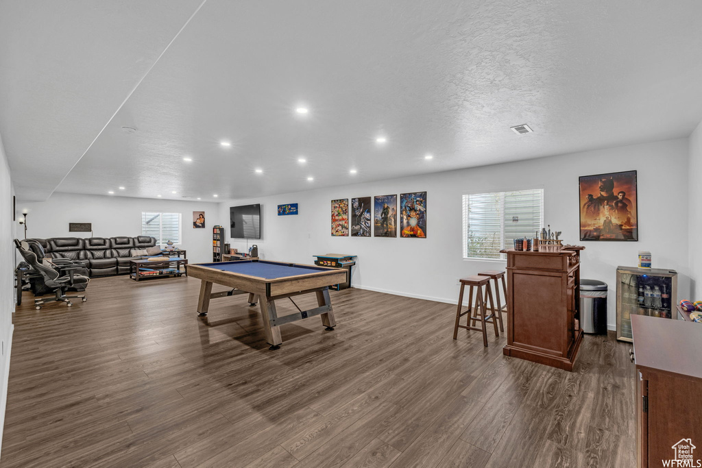 Game room featuring dark hardwood / wood-style flooring, billiards, beverage cooler, and a textured ceiling