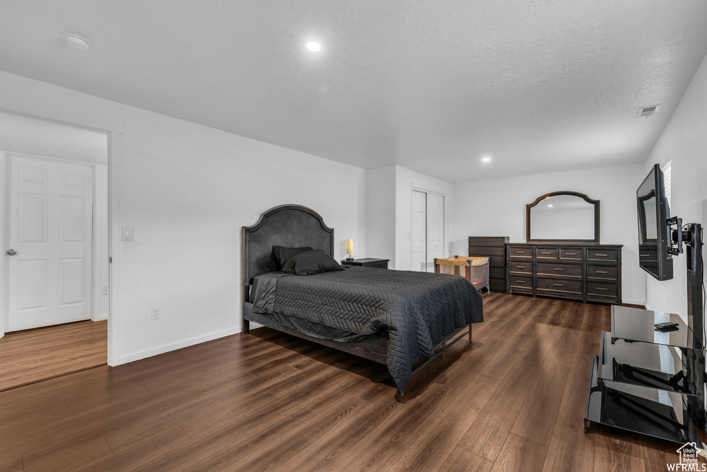Bedroom with dark hardwood / wood-style floors and a closet