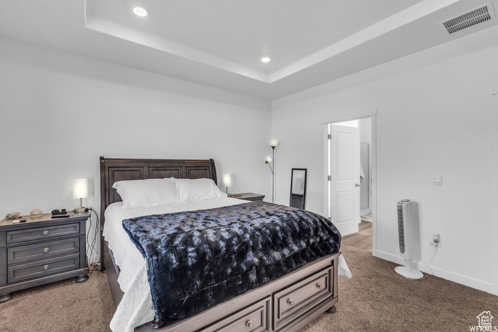 Carpeted bedroom with ensuite bath and a tray ceiling