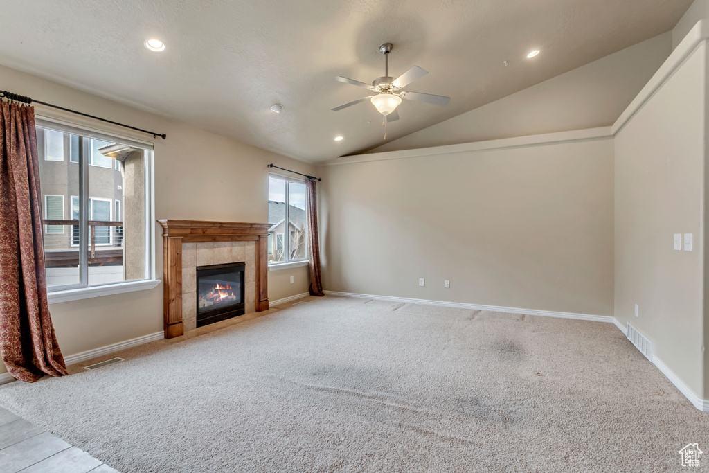 Unfurnished living room with a fireplace, lofted ceiling, ceiling fan, and light colored carpet