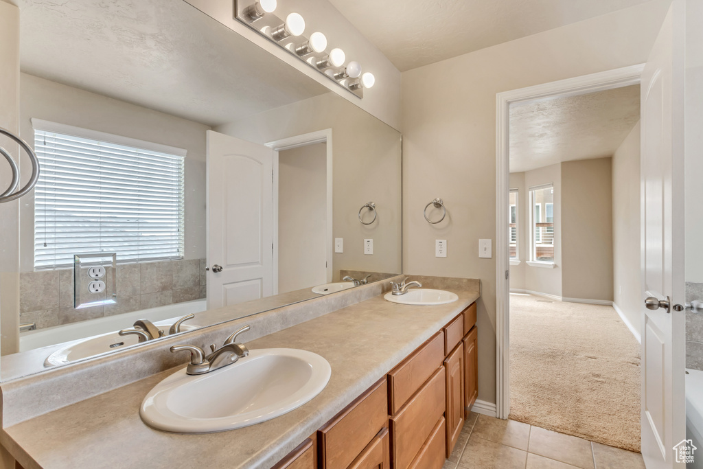 Bathroom featuring a tub, large vanity, tile floors, and double sink