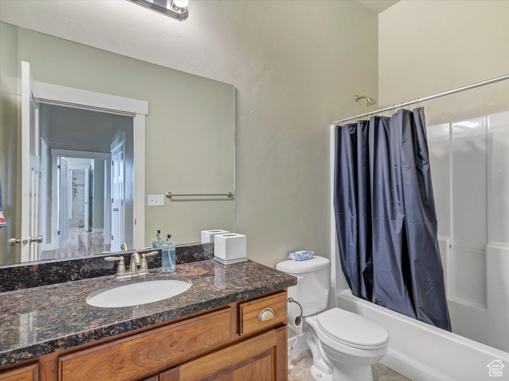 Full bathroom with vanity, toilet, shower / bath combo with shower curtain, and tile floors