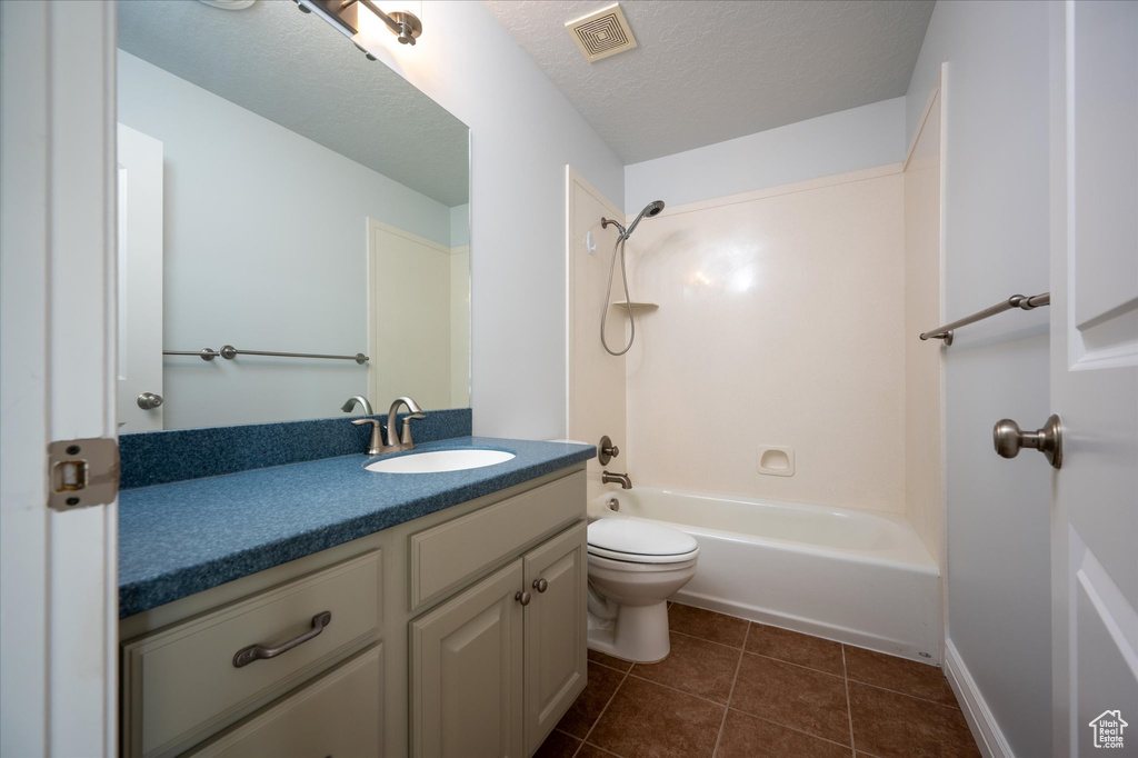 Full bathroom featuring a textured ceiling, toilet, bathtub / shower combination, large vanity, and tile flooring