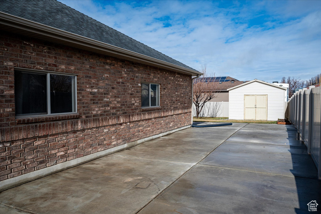 View of side of property featuring a storage unit and a patio