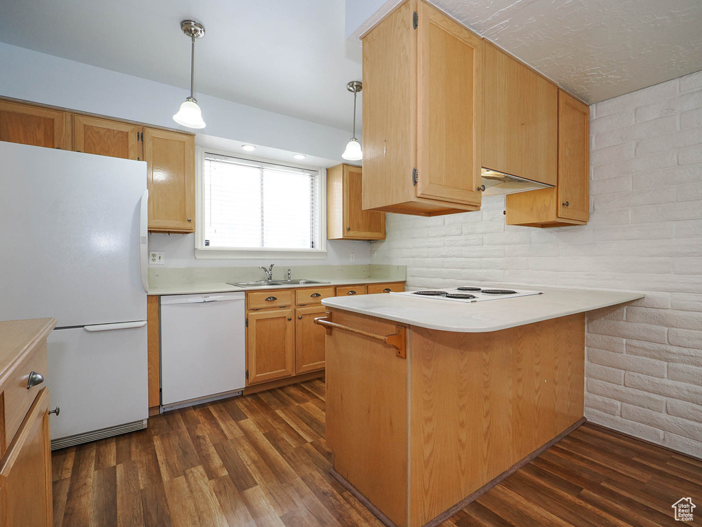 Kitchen with white appliances, dark wood-type flooring, pendant lighting, and kitchen peninsula