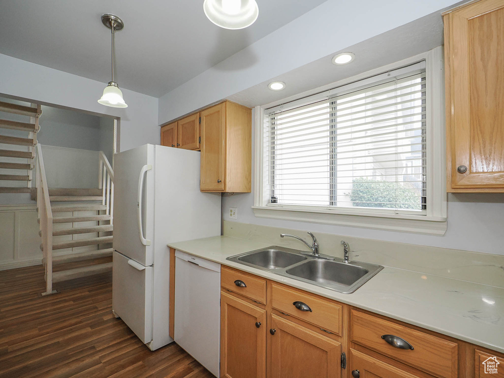 Kitchen with dark wood-type flooring, sink, white dishwasher, and decorative light fixtures